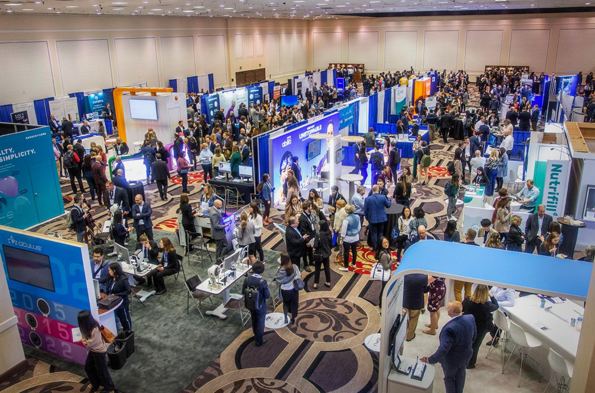 Busy exhibition hall with attendees visiting sponsor and exhibitor booths